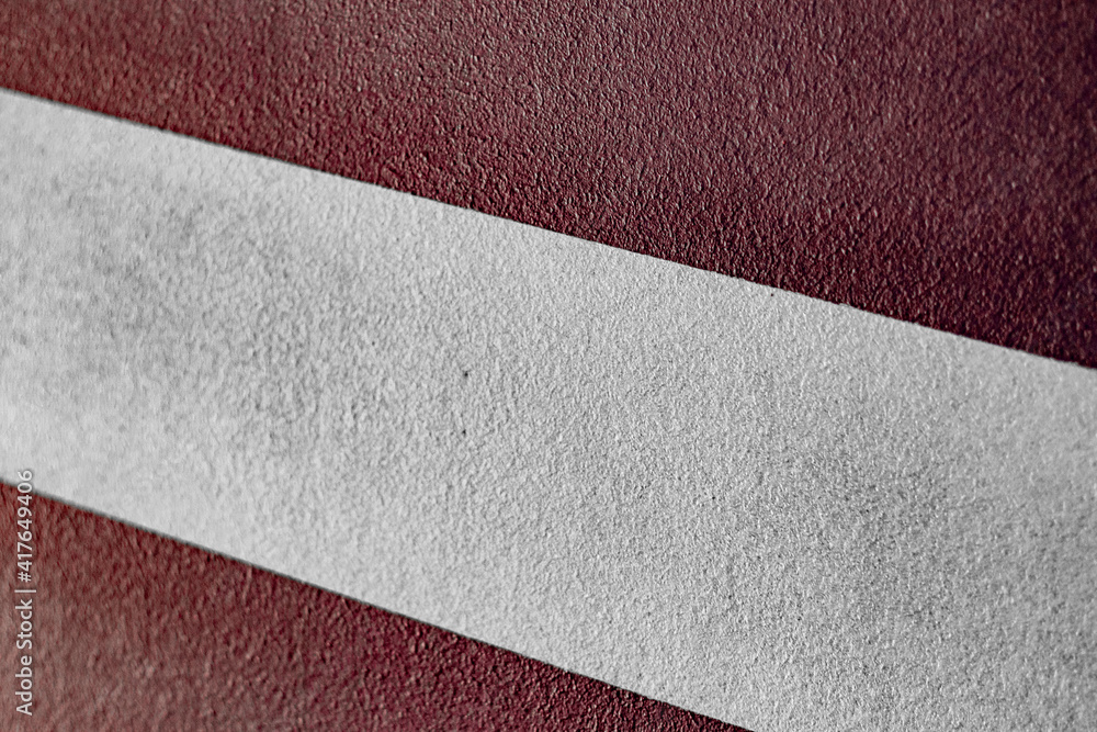 On the maroon paved road there is a diagonal white stripe On the maroon paved road there is a diagonal white stripe