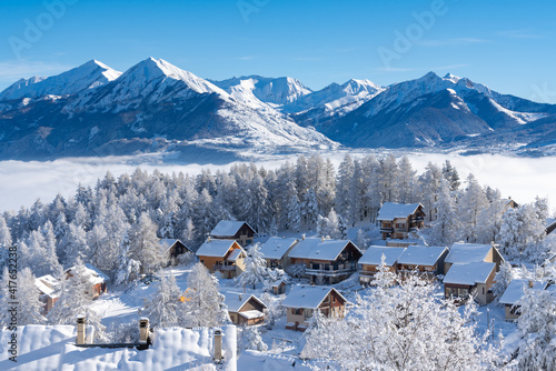 Fresh snow covers roofs and trees of Laye winter ski resort in Champsaur, French Alps. Hautes-Alpes, France photo