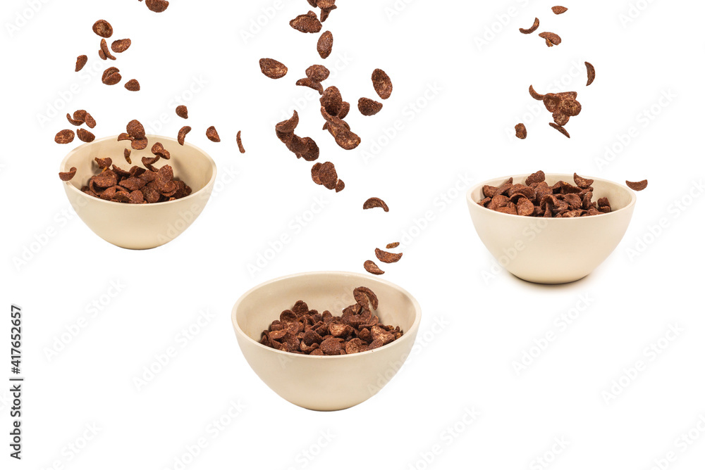 Chocolate corn flakes falling to the white bowl isolated on white. Motion. Chocolate corn flakes falling to the white bowl isolated on white. Motion.