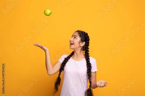 Portrait of a cheerful young woman juggling green apple