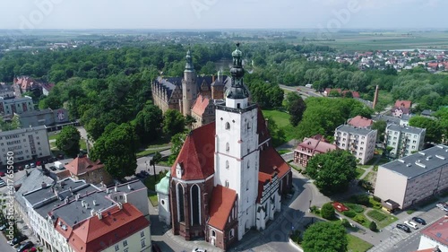 Basilica in Oleśnica in the Lower Silesian Voivodeship in Poland. On the second Plan, the historic castle of the Dukes of Oleśnica. Sunny summer day on a drone video.