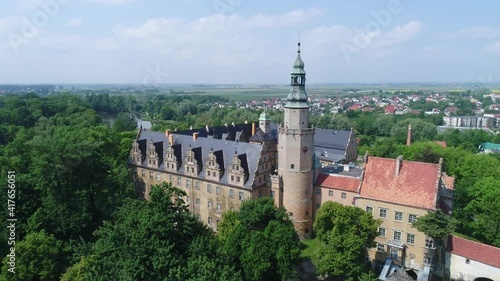 Castle of the Dukes of Oleśnica in Oleśnica In Poland from a great height on a video from a drone. Historical building surrounded by a park with lots of trees. Sunny summer day.