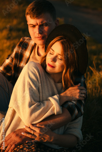 Young loving couple sitting on grass in strong hugs