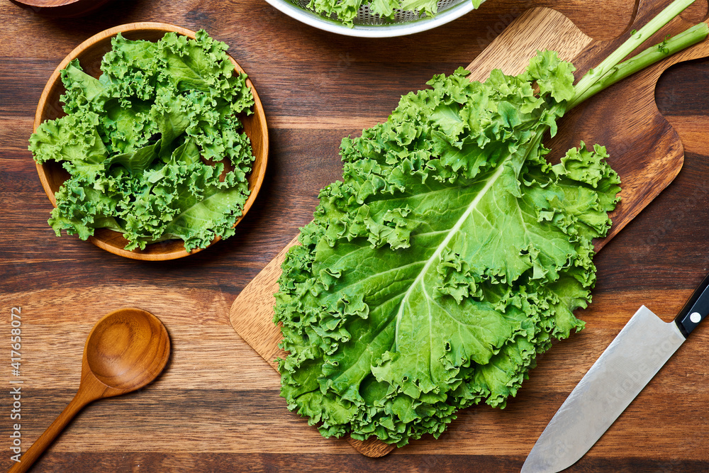 concept of fresh kale leaves salad on wooden table background. preparing green kale leaves salad food in the kitchen. flat lay, top view concept of fresh kale leaves salad on wooden table background. preparing green kale leaves salad food in the kitchen. flat lay, top view