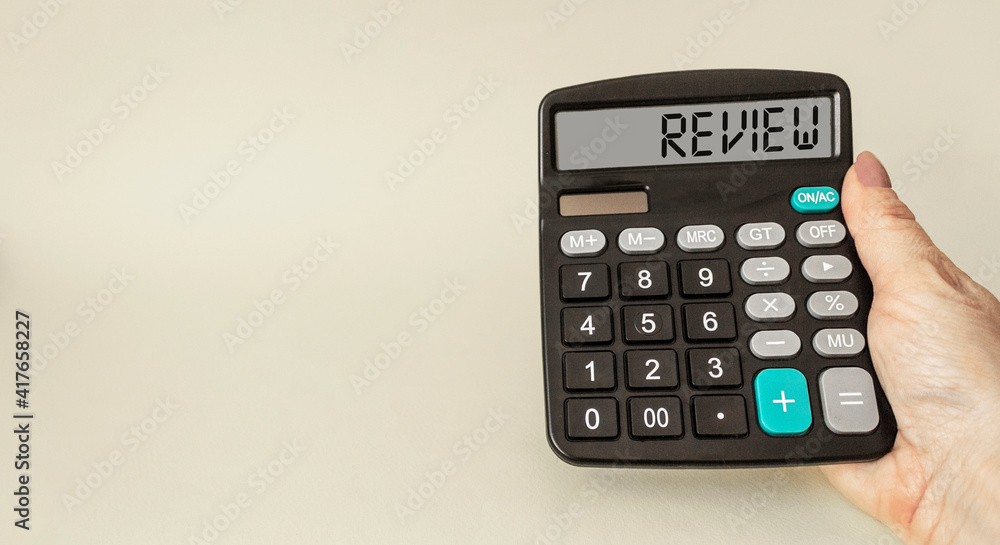 A female hand holds the calculator, the word REVIEW is written on the display. A female hand holds the calculator, the word REVIEW is written on the display.