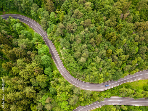 Winding road aerial view by drone. Brasov, Romania. There are huge snow mountains and long winding road in this area. This is a great place to drive and stop during a road trip. © Rafaila Gheorghita