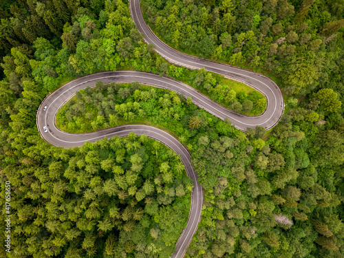 Fototapeta Naklejka Na Ścianę i Meble -  Winding road aerial view by drone. Brasov, Romania. There are huge snow mountains and long winding road in this area. This is a great place to drive and stop during a road trip.