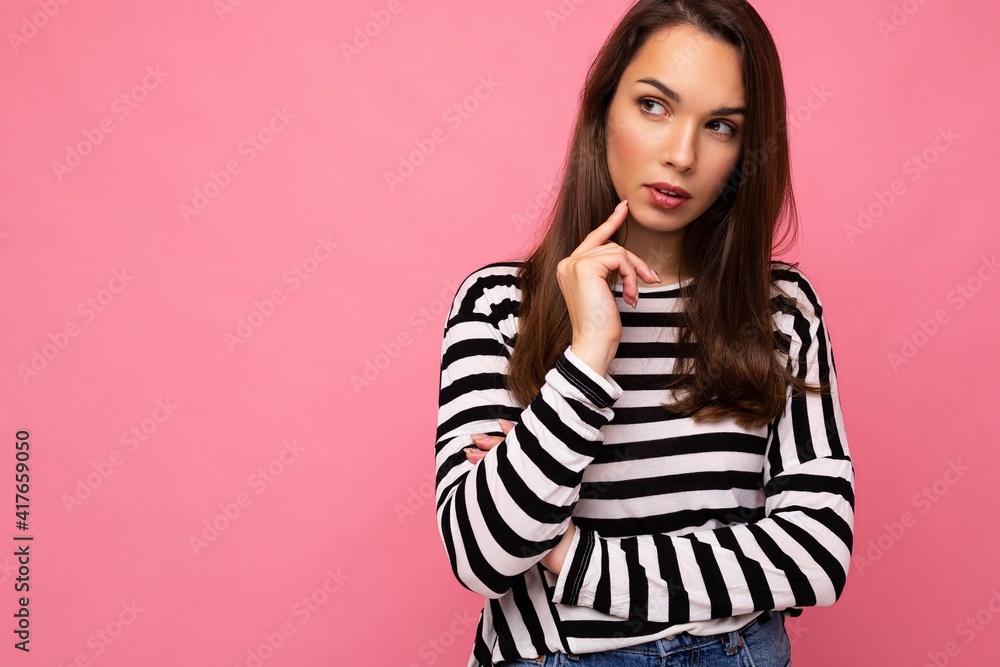 Shot of young positive happy thoughtful nice cute brunette woman with sincere emotions wearing casual striped sweater isolated on pink background with empty space and thinking Shot of young positive happy thoughtful nice cute brunette woman with sincere emotions wearing casual striped sweater isolated on pink background with empty space and thinking