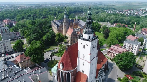 Basilica in Oleśnica in the Lower Silesian Voivodeship in Poland. On the second Plan, the historic castle of the Dukes of Oleśnica. Sunny summer day on a drone video.
 photo