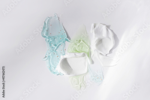 фотографія Facial care products smeared on a white background, kram, shaving foam, scrub