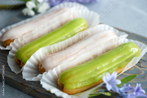 Vanilla and pistachio eclairs on wooden board on table