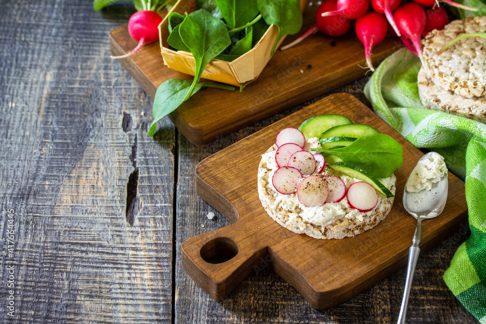 Healthy breakfast. Crunchy crispbread Sandwiches with ricotta, radish and fresh cucumber on a wooden table. Copy space.