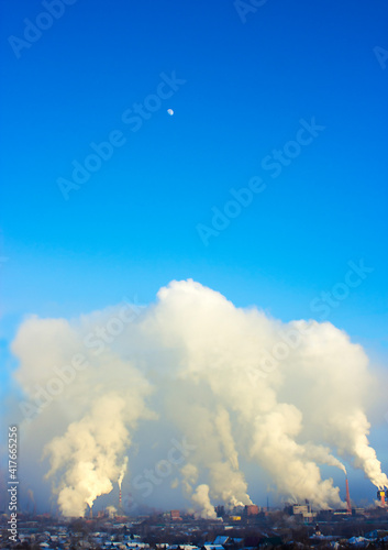 gray polluting smoke from the chimneys of the enterprise on the background of the blue sky with the moon