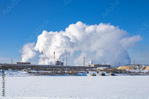 A large industrial complex against the backdrop of a bright blue sky.