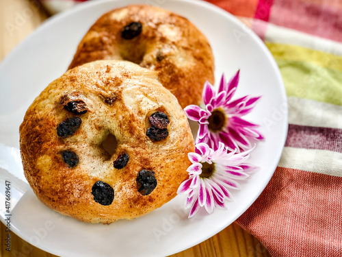 Homemade Cinnamon Raisin Bagels on Plaid Napkin and Wood Background.