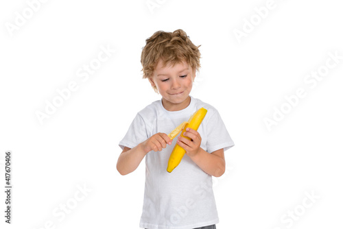 A little boy peels a ripe banana.