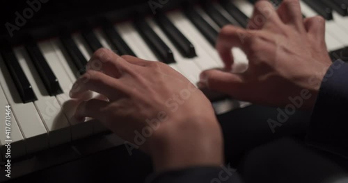 Close up of musician hands playing bass guitar neck in dark studio background.