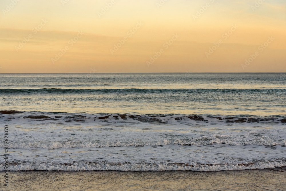  wave at sea breaking on the beach, in a quiet sunrise, with the sea calm