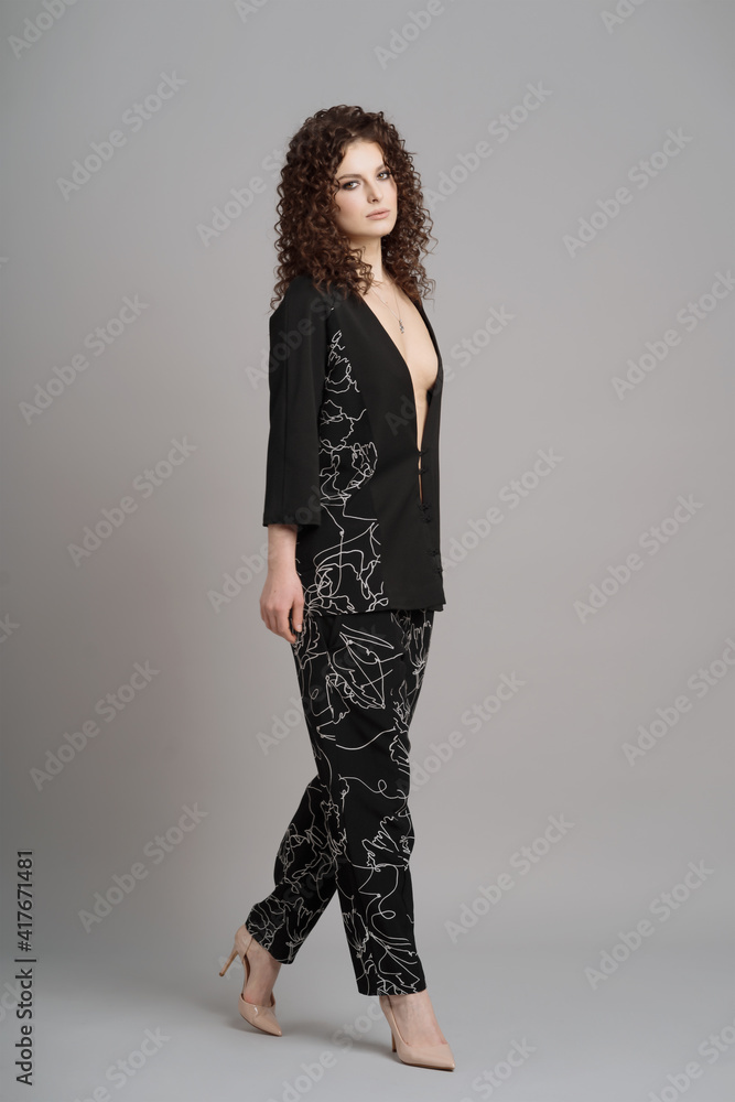 Full length Portrait of cute woman with modern hairdo in stylish clothes in black stylish costume on gray background Full length Portrait of cute woman with modern hairdo in stylish clothes in black stylish costume on gray background
