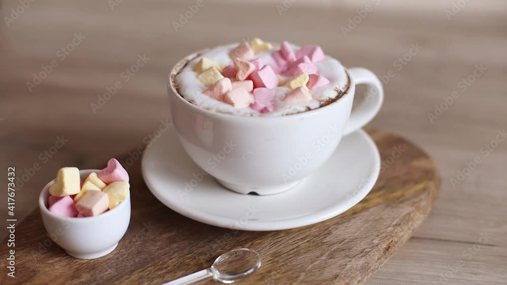 Cappuccino coffee in ceramic cup with love marshmallow candy on wooden board. Home making coffee.