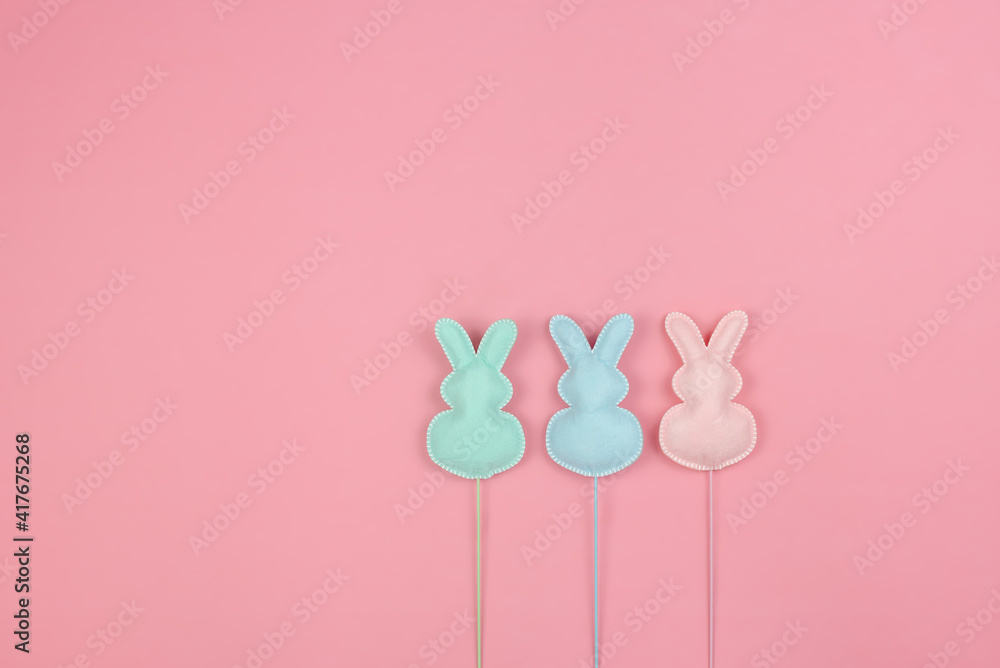 Three pastel bunnies in a row on a pink background Three pastel bunnies in a row on a pink background