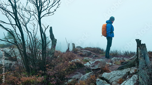 Outdoor Wanderer Frau mit Rucksack und dicker Kleidung im Nebel auf Felsvorsprung schroffe karge Natur Ödland Berge Gebirge Harz Alpen Norwegen Schweden Finnland Ausblick Weitblick kalt 