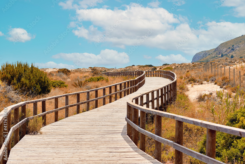Wooden boardwalk leading through sandy dunes to Sea. Spain