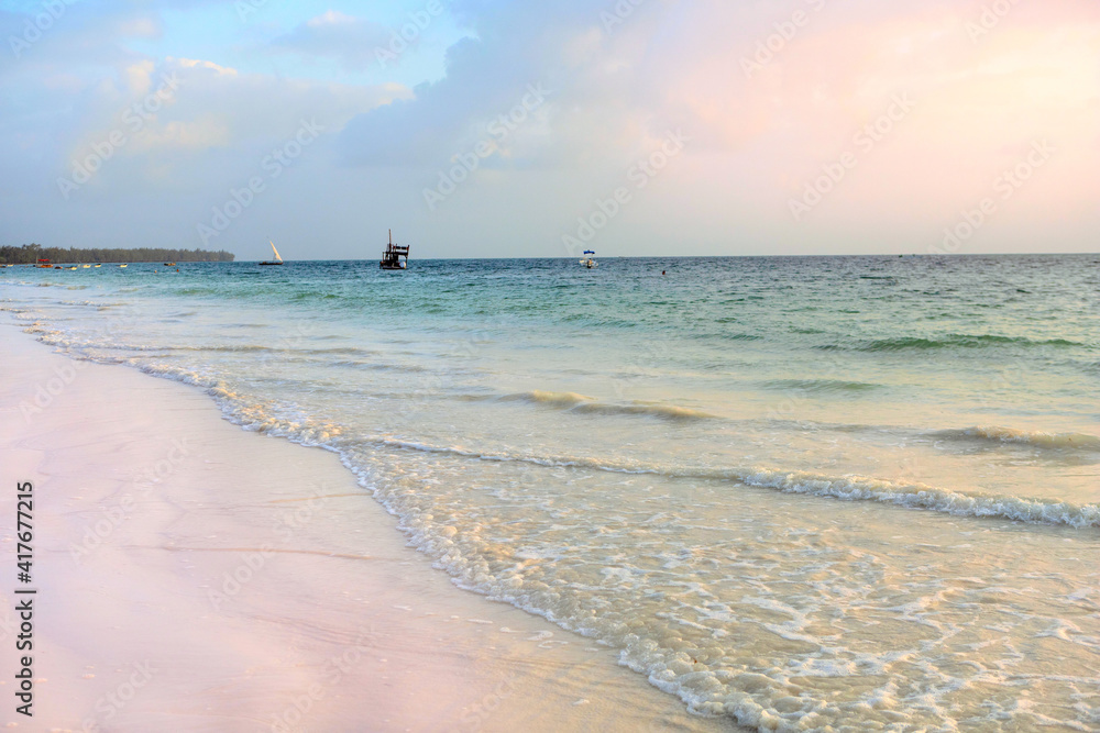 Indian ocean coast at sunset. Sunset light on the beach. Holidays on the island of Zanzibar. Beautiful landscape. The horizon line at the border of sky and water