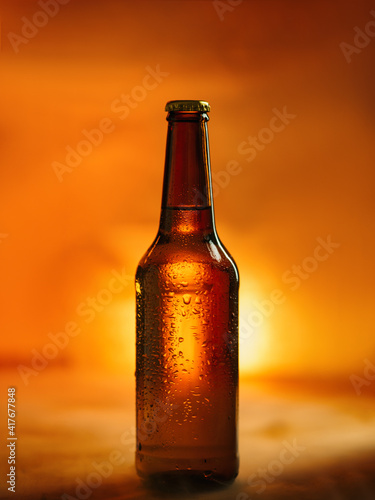 Close-up of a cold beer bottle in water drops on a wooden background