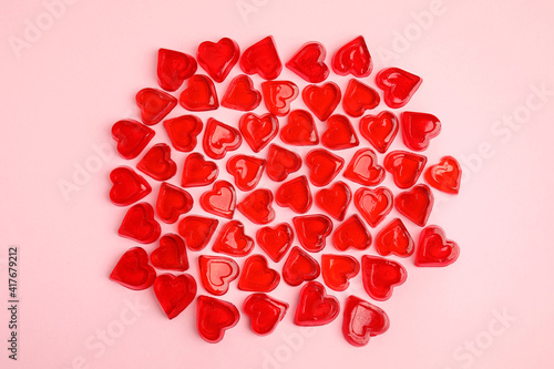 Sweet heart shaped jelly candies on pink background, flat lay