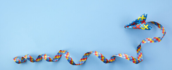 Autism awareness. paper plane in origami style with autism awareness ribbon on blue background.