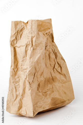 Crumpled paper bag with greasy spots on a white isolated background. Recycling of secondary waste