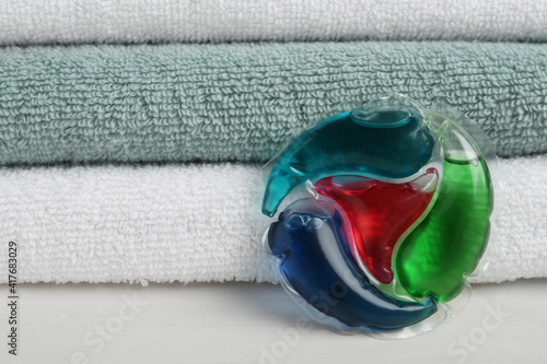 Laundry capsule and towels on white table, closeup. Space for text photo