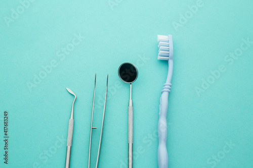 Dentist tools close-up. Professional steel dental instruments with a mirror on light blue background. Dental health and teethcare concept.