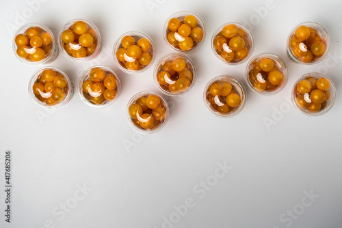 top view of many plastic cocktail packages of orange cherry tomatoes flat lay on the table