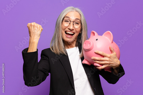Foto senior pretty businesswoman with a piggy bank