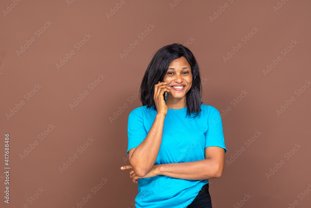 beautiful african young lady smiling while making a phone call, with copy space beautiful african young lady smiling while making a phone call, with copy space