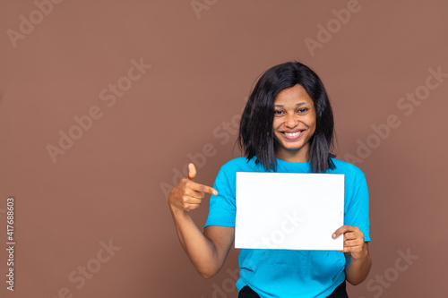 excited beautiful young african lady holding an empty sign and pointing to it, advertising concept