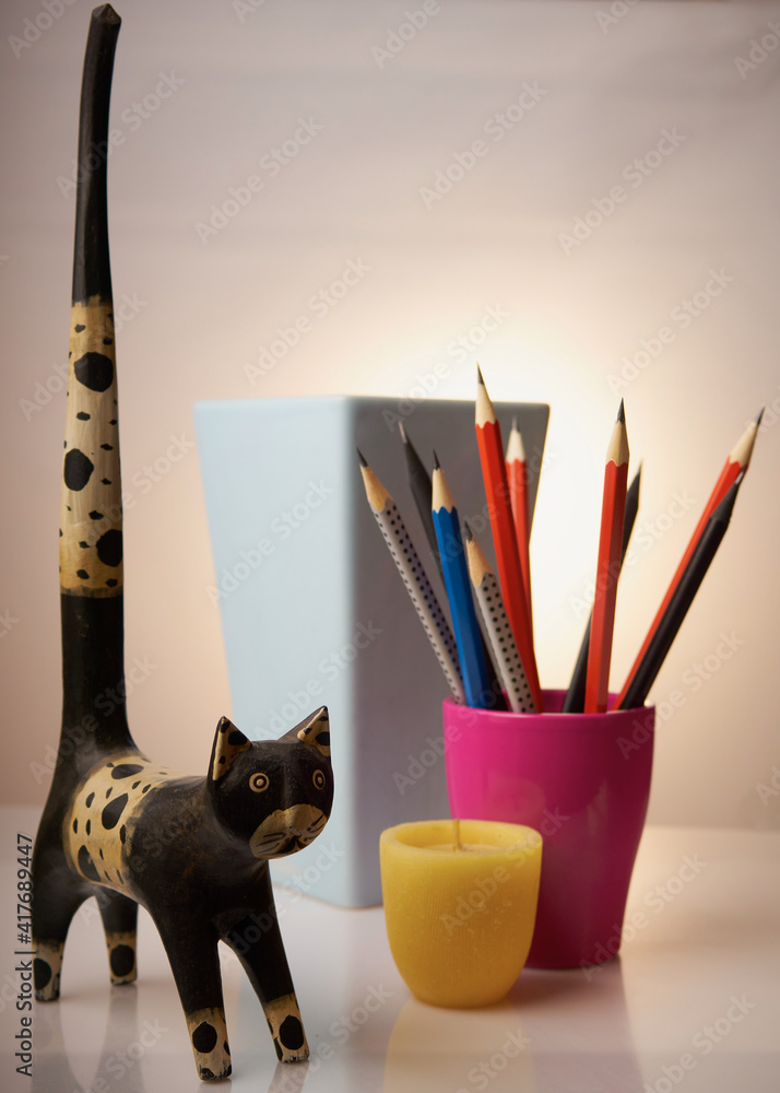 Bleistifte, Stillleben, Ton-Töpfe - blau, Terrakotta, Magenta. Kleine gelbe Kerze.
Holzkater mit dem langen Schwanz