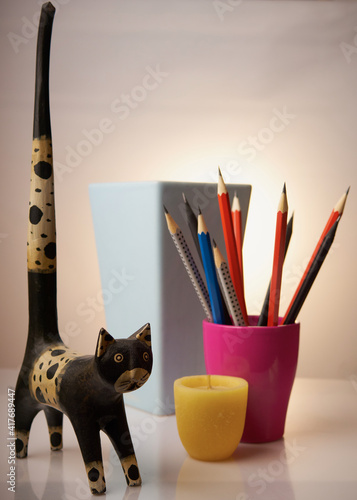 Bleistifte, Stillleben, Ton-Töpfe - blau, Terrakotta, Magenta. Kleine gelbe Kerze.
Holzkater mit dem langen Schwanz