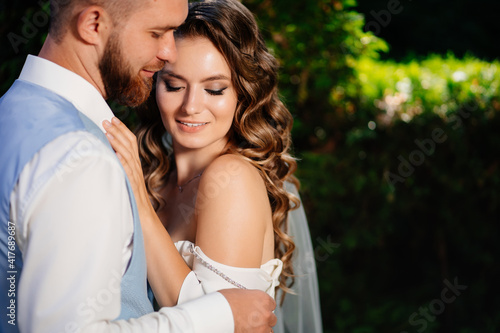 Happy and beautiful bride and groom gently cuddle in the park © andrey