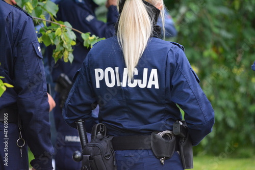 Blond policjantka na patroluje na tle zieleni.  photo