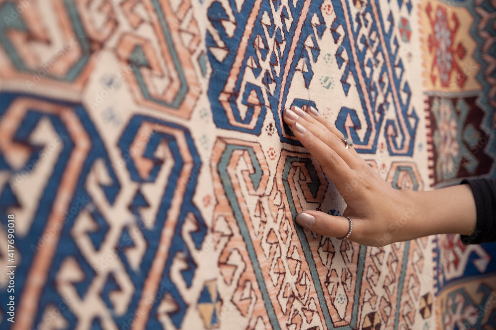 Young woman touching the traditional turkish carpet.Traditional culture products. - obrazy, fototapety, plakaty 