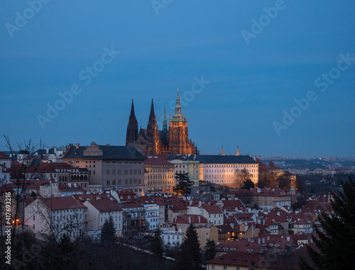 Evening view of illuminated St. Vitus Cathedral gothic churche and Prague Castle panorama, hradcany and Mala Strana quarter from Petrin hill, blue sky background
