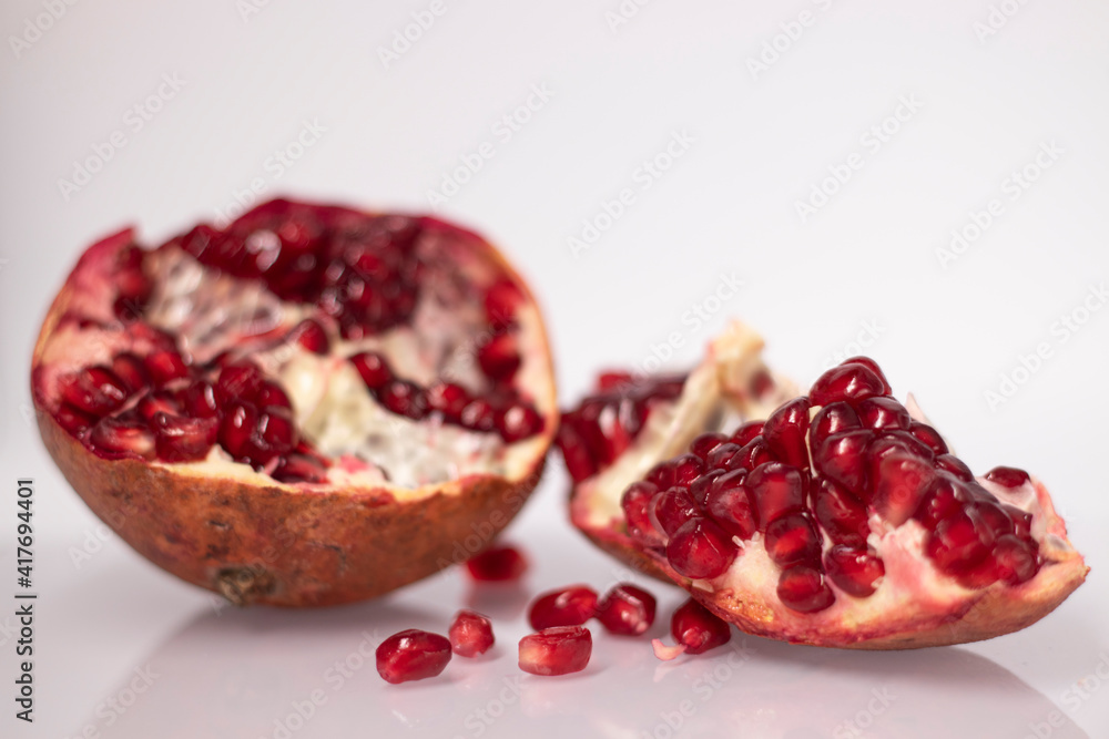 Fresh ripe sliced pomegranate fruit with red seeds isolated on white background Fresh ripe sliced pomegranate fruit with red seeds isolated on white background