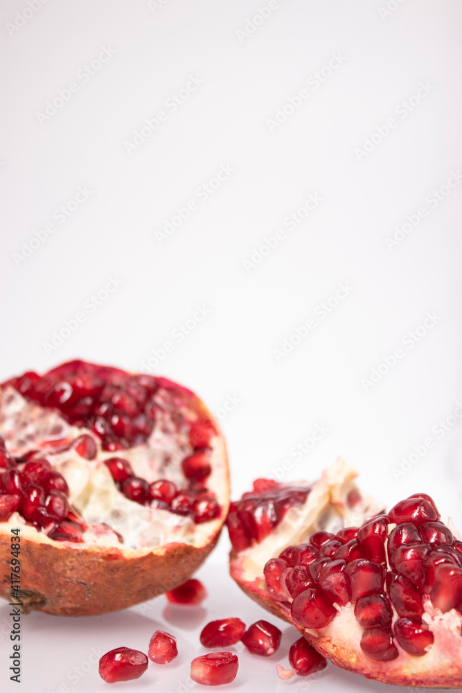 Fresh ripe sliced pomegranate fruit with red seeds isolated on white background Fresh ripe sliced pomegranate fruit with red seeds isolated on white background