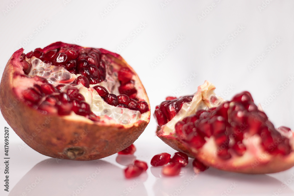 Fresh ripe sliced pomegranate fruit with red seeds isolated on white background Fresh ripe sliced pomegranate fruit with red seeds isolated on white background