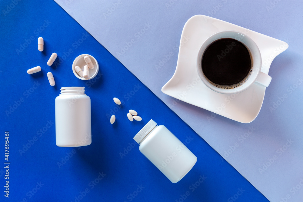 Two white bottle, pills, coffee cup on blue background. Concept Insomnia, full moon time, sleep problems, soporific. Mockup, Top view, Flat lay, Copy space. Two white bottle, pills, coffee cup on blue background. Concept Insomnia, full moon time, sleep problems, soporific. Mockup, Top view, Flat lay, Copy space.