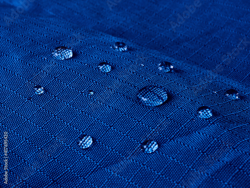 Water drops on waterproof membrane fabric. Detail view of texture of blue waterproof cloth. photo