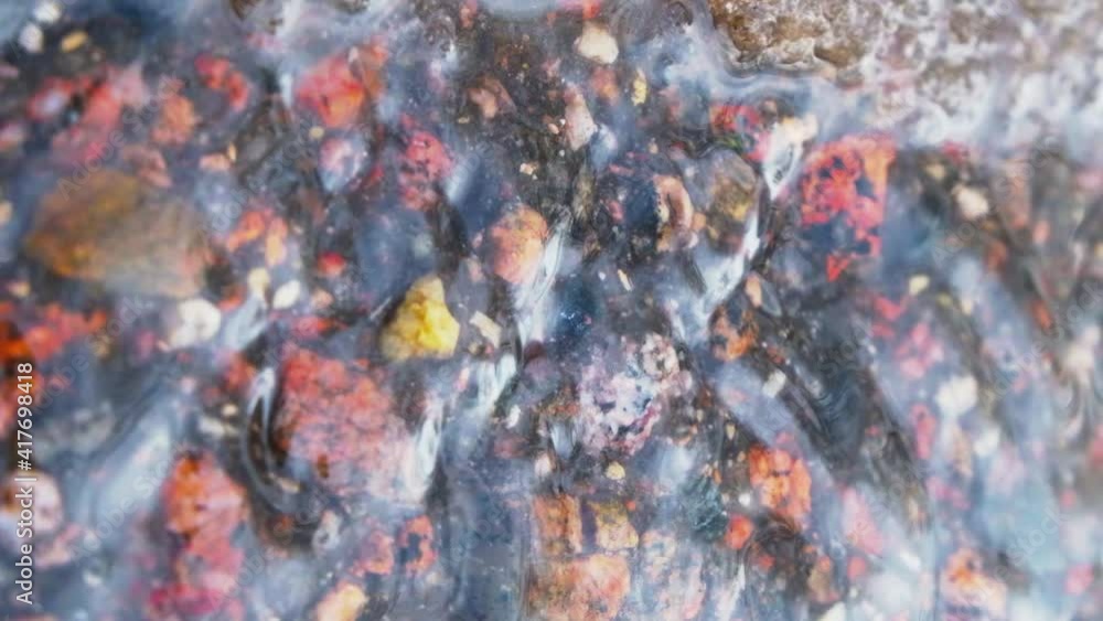 A winter brook slowly flowing on a colorful rocks. A winter brook slowly flowing on a colorful rocks.